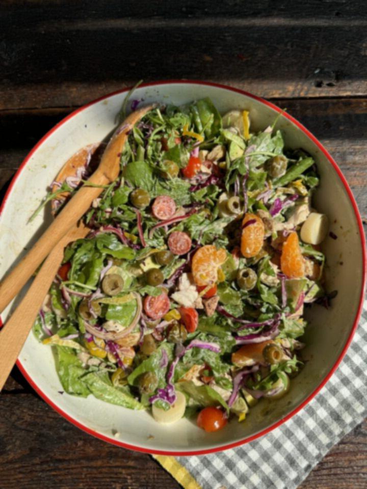 Whole30 κομμένη σαλάτα με εσπεριδοειδή σε μεγάλο μπολ με δύο ξύλινες κουτάλες και μια καρό πετσέτα